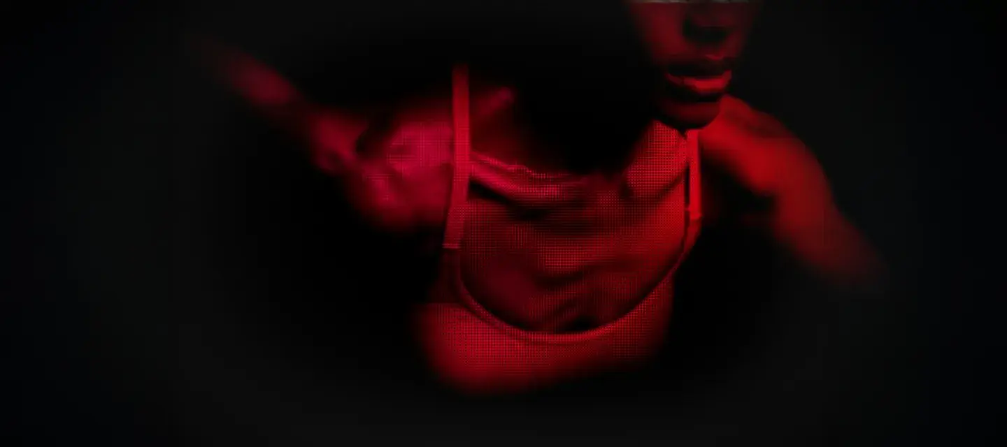 A bust of a fit African-American woman in red light showing movement